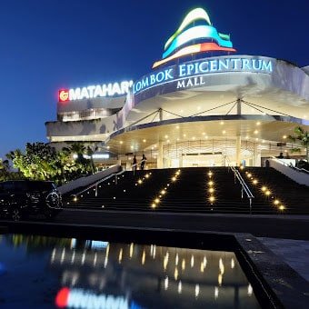 A bustling scene inside Epicentrum Mall, with shoppers browsing through various stores and colorful displays, beneath the bright lights of the shopping center