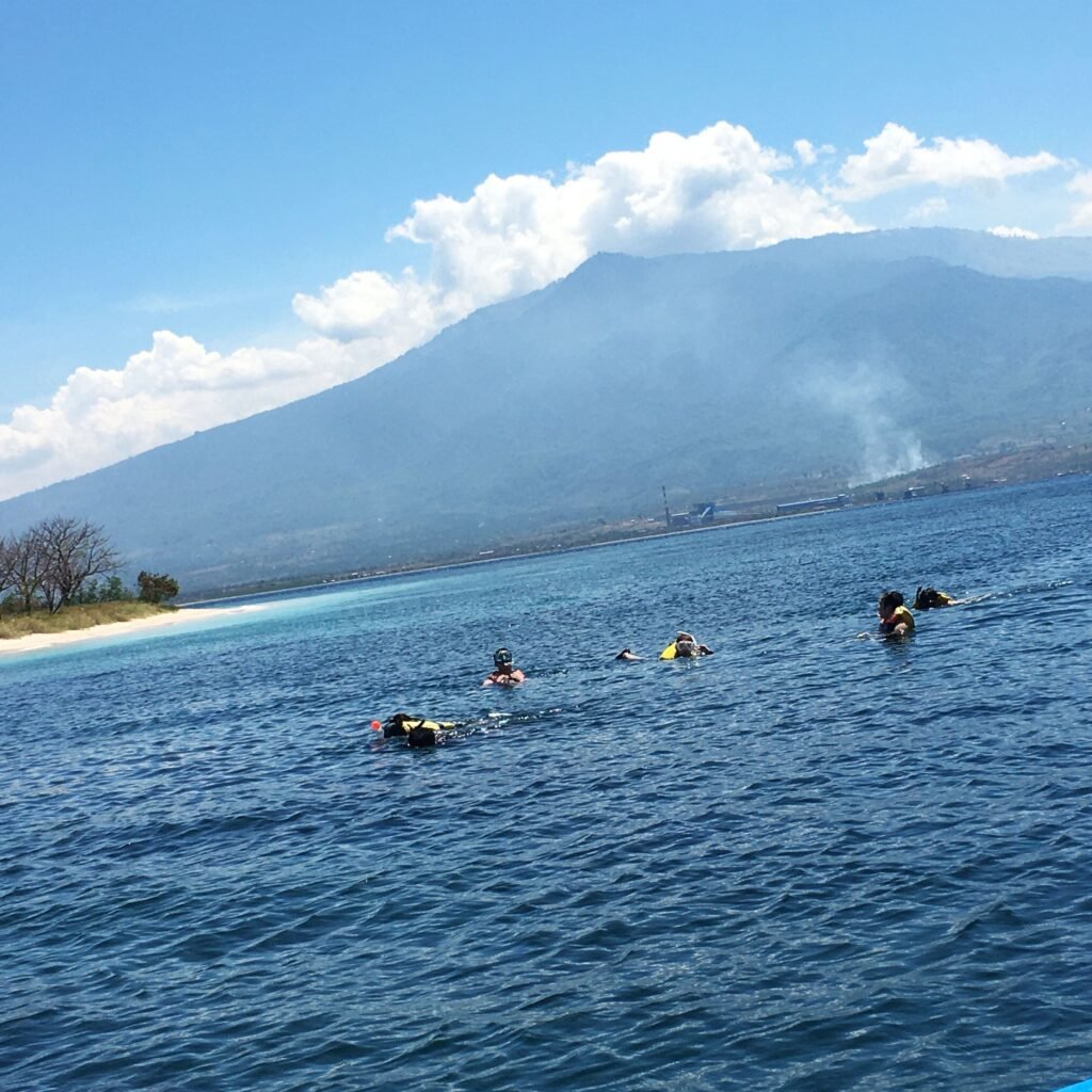 A group of snorkelers enjoying the crystal-clear waters surrounding Gili Kondo, observing vibrant coral reefs and colorful marine life beneath the surface during their snorkeling trip