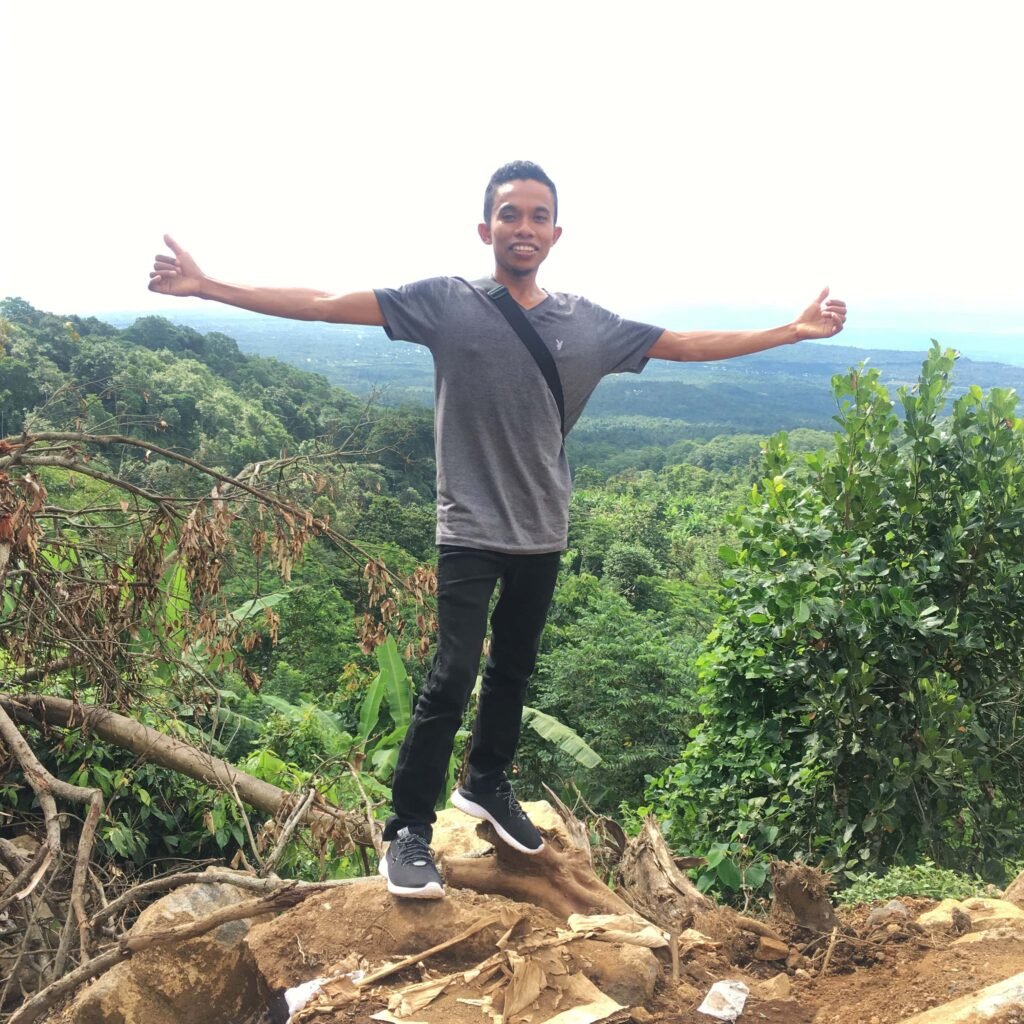 A panoramic view of Selong Hill in Sembalun, with rolling green slopes under a clear blue sky, offering a serene and picturesque vista