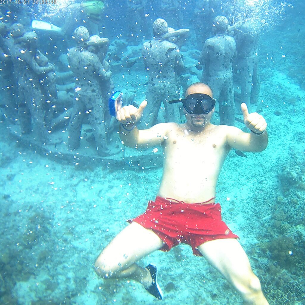 Crystal-clear waters envelop a snorkeler exploring the vibrant underwater world near Statue Gili Meno.